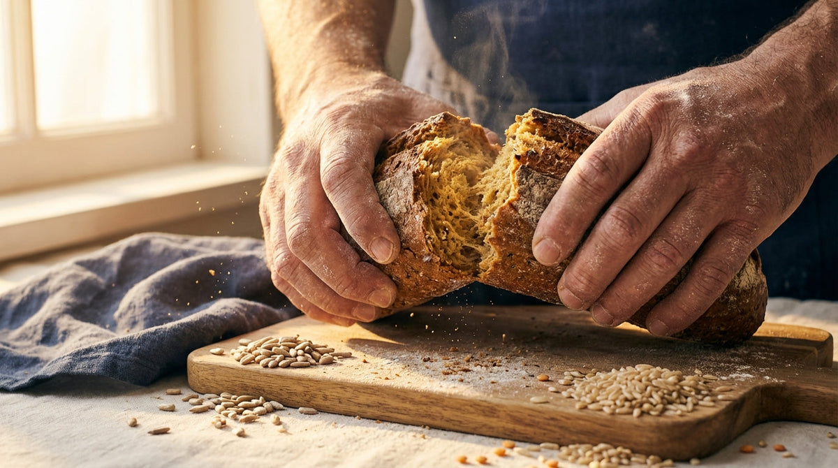 Close-up of hands breaking whole grain bread revealing thiamine-rich golden interior with seeds and grains