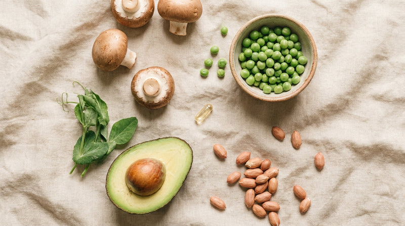 Overhead flat lay of niacinamide-rich foods including mushrooms avocado and peas on warm linen