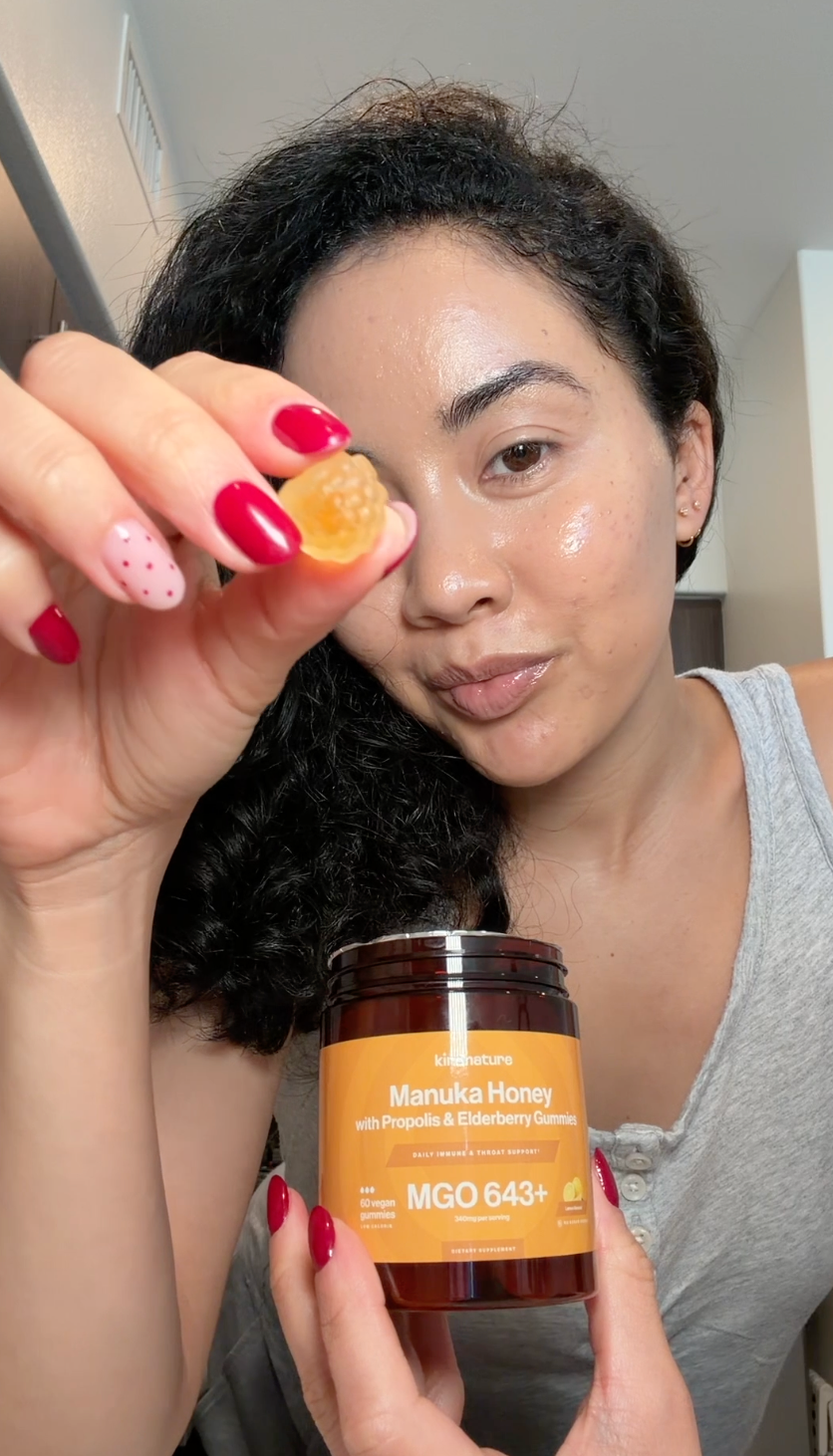 Woman holding Kindnature Manuka Honey Gummies and a gummy
